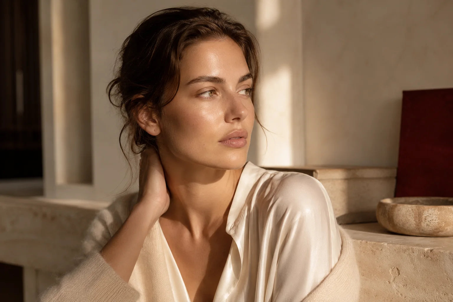 A woman in warm light, wearing an ivory blouse